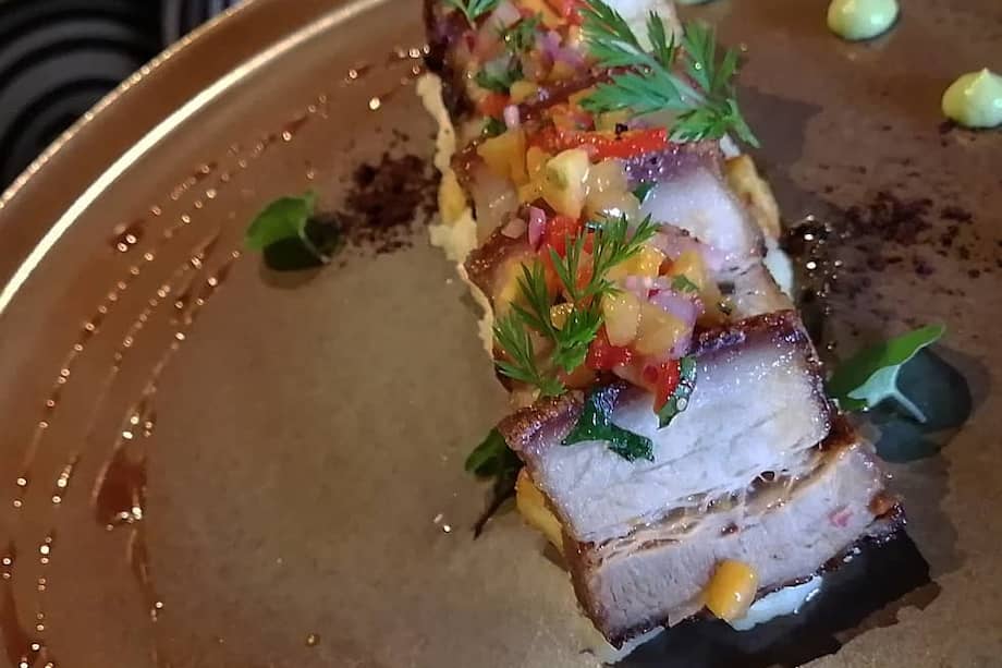 Tocino crocante glaseado en panela con limón mandarino, servido con puré de yuca con queso costeño frito y ají de uchuvas