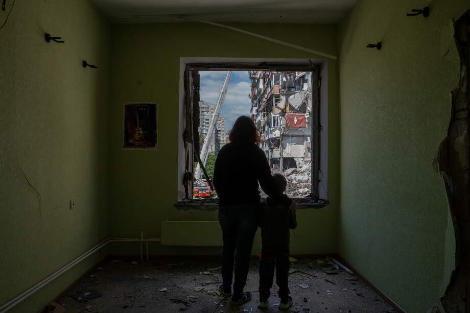 Un retrato colaborativo de Janna y su hijo Oliver, de seis años, mientras miran a través de la ventana destrozada de su jardín de infancia hacia un edificio residencial de nueve pisos destruido por un ataque con misiles rusos ocurrido esa misma mañana.
24 personas murieron. Kyiv, Ucrania. 14 de mayo de 2026.