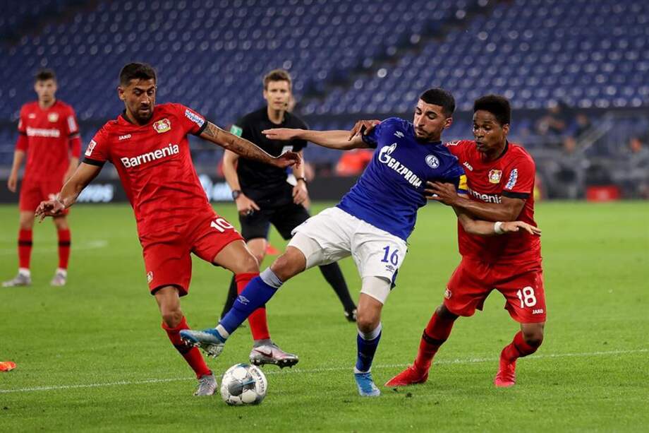 Nassim Boujellab, capitán del Schalke 04, en un forcejeo con Demirbay y Wendell, volantes ofensivos del Bayern Leverkusen.