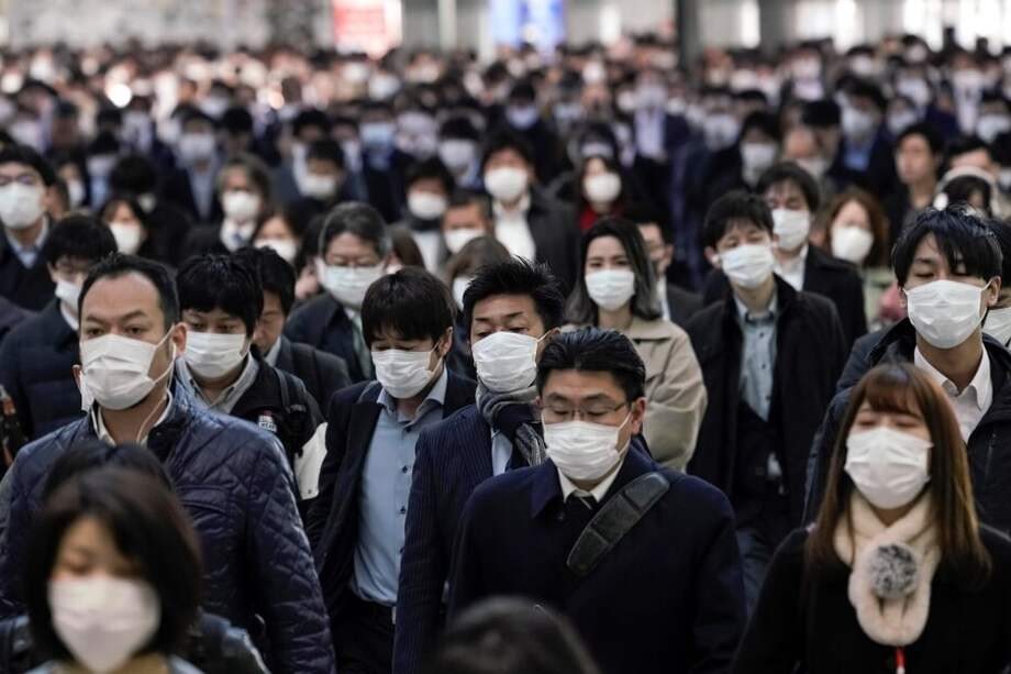Trabajadores protegidos con mascarillas acuden a sus oficinas en Tokio, Japón, este lunes, un día antes de las medidas del Gobierno. / EFE