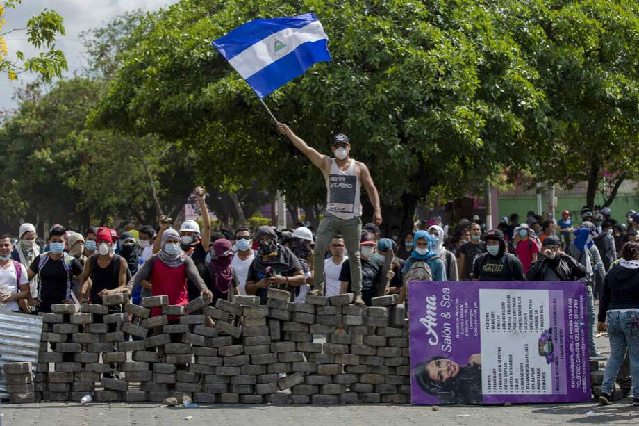 Un joven levanta una bandera de Nicaragua sobre una barricada de adoquines durante protestas en Managua, Nicaragua. / EFE