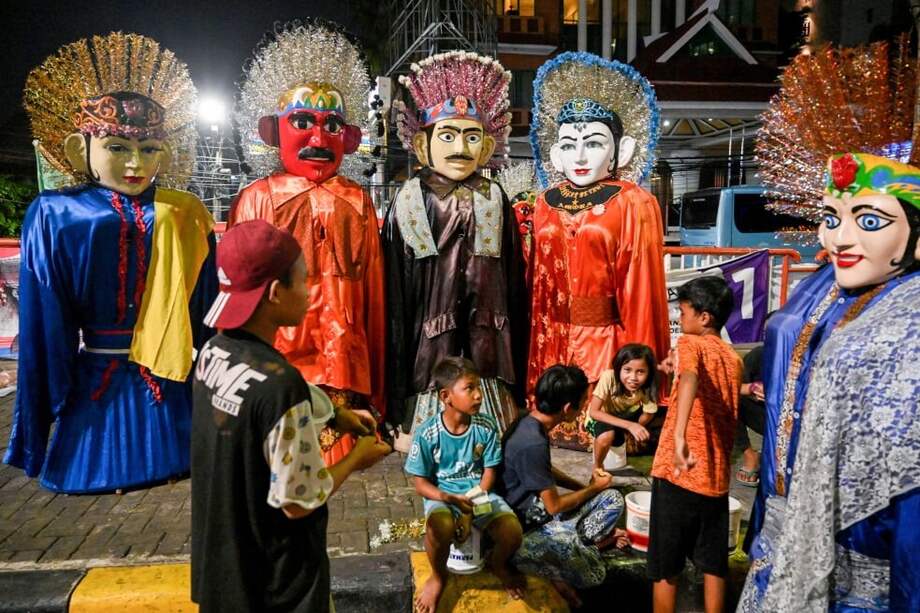 Algunos niños se ganan la vida en Indonesia disfrazándose de las brillantes estatuas de dos metros, conocidas como Ondel-ondel, y caminando por las calles de Yakarta. / AFP