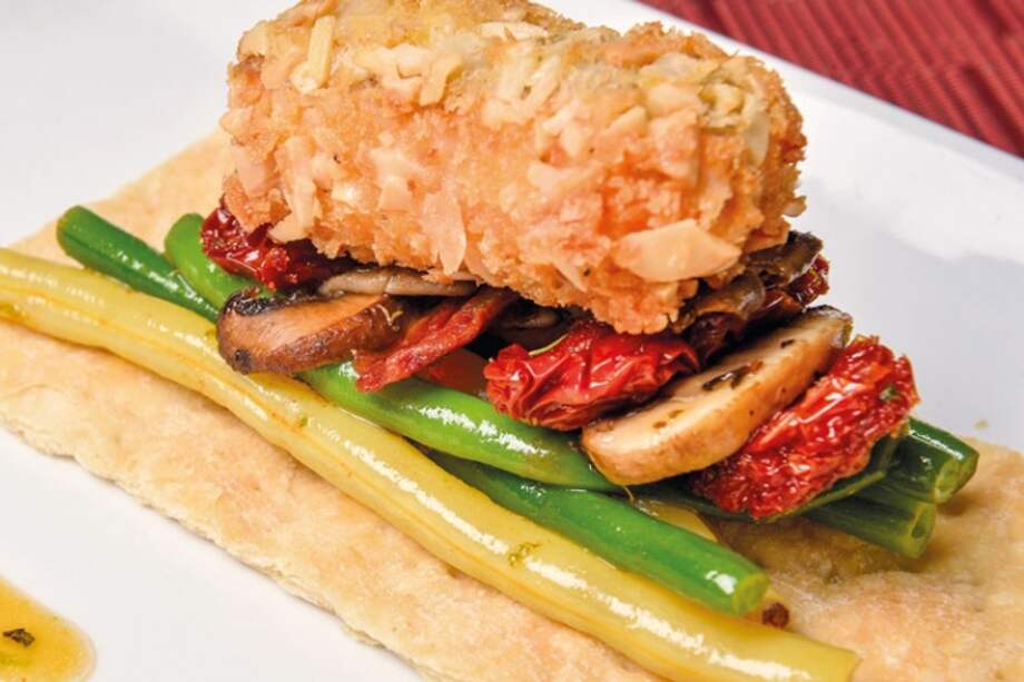 Palitos de salmón apanados con almendras sobre habichuelines y tomates secos