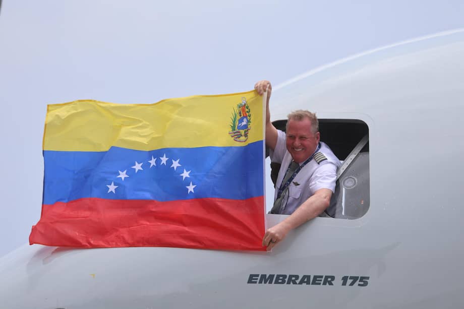 Una persona sostiene una bandera de Venezuela durante el recibimiento del primer vuelo comercial directo entre Estados Unidos y Venezuela luego de siete años de conexiones suspendidas y bajo la operación de American Airlines.