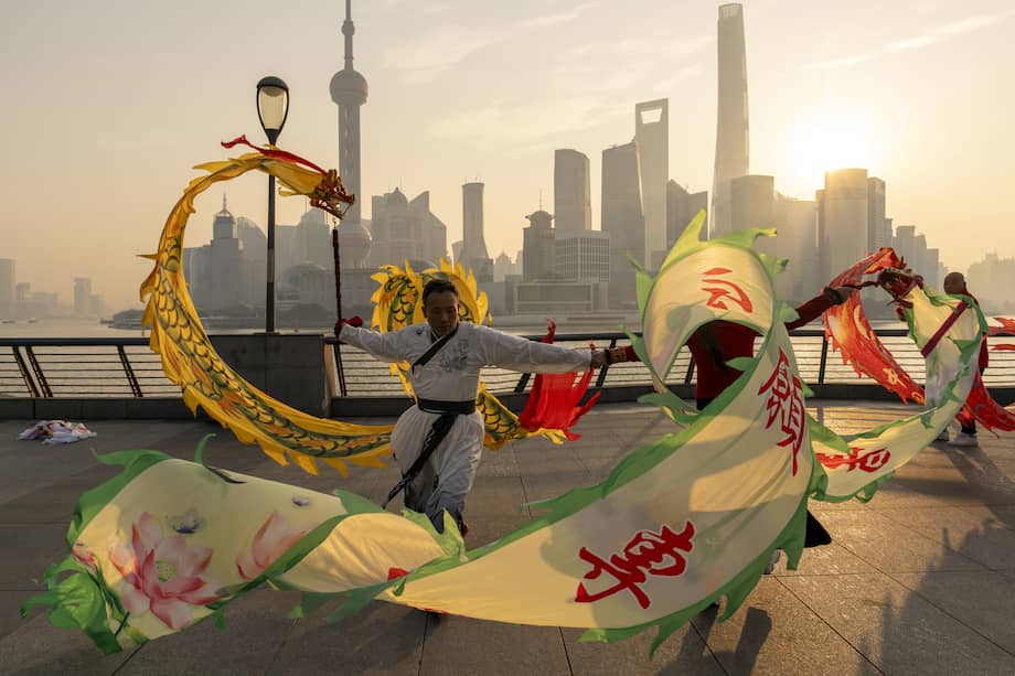 La gente vuela cometas con forma de dragón en el Bund frente a los edificios del distrito financiero de Lujiazui de Pudong en Shanghái, China.