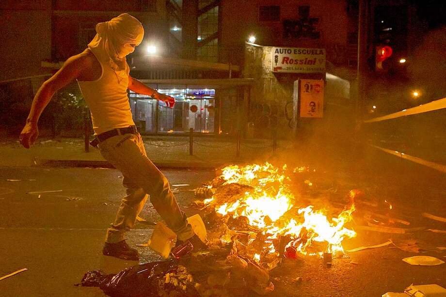 Un hombre prende fuego a barricadas durante una protesta contra el gobierno del presidente venezolano, Nicolás Maduro, el jueves, en el sector Altamira, en Caracas. / EFE