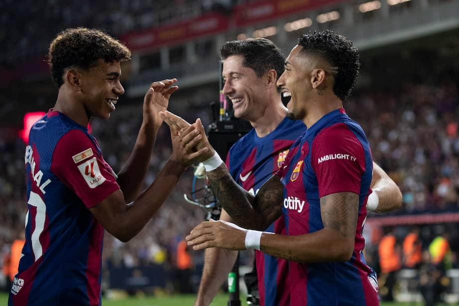 El delantero brasileño del FC Barcelona, Raphinha (d), celebra el cuarto gol del equipo blaugrana durante el encuentro correspondiente a la quinta jornada de primera división que disputaron hoy frente al Betis en el estadio Olímpico de Montjuic.