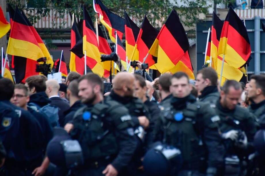 Partidarios del partido de extrema derecha Alternativa para Alemania (AfD) ondean banderas alemanas mientras caminan detrás de un grupo de policías antidisturbios durante una manifestación en Chemnitz, en el este de Alemania.