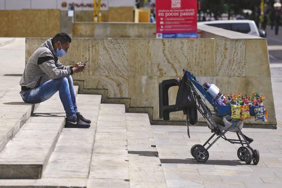 A street vendor wearing a protective mask looks at a smartphone as he waits for customers during a national strike in Bogota, Colombia, on Monday, Sept. 21, 2020. Nationwide marches are scheduled for Monday to protest, among others, police brutality and the murder of social leaders. Photographer: Ivan Valencia/Bloomberg