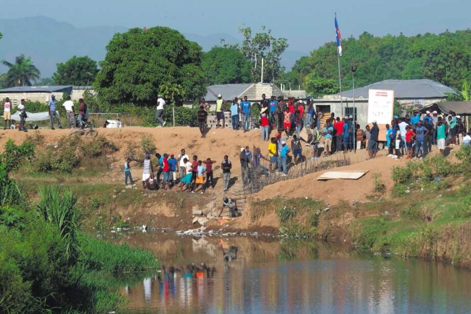 La gente observa desde la orilla del río Masacre mientras los trabajadores construyen un canal que llega al río.