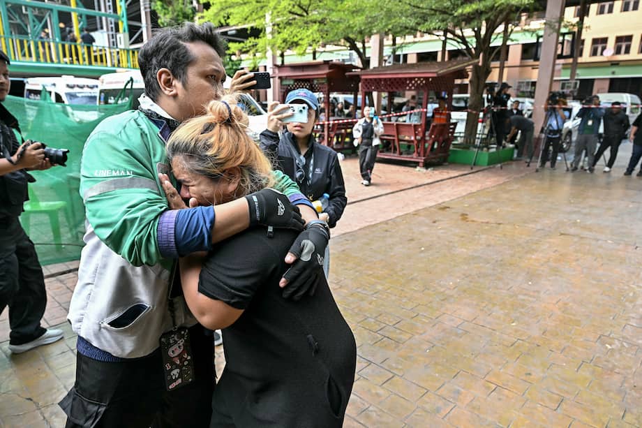 Los familiares de una víctima del tiroteo en una escuela lloran mientras los cuerpos de los fallecidos son introducidos en ambulancias en la escuela del distrito de Bang Kruai.