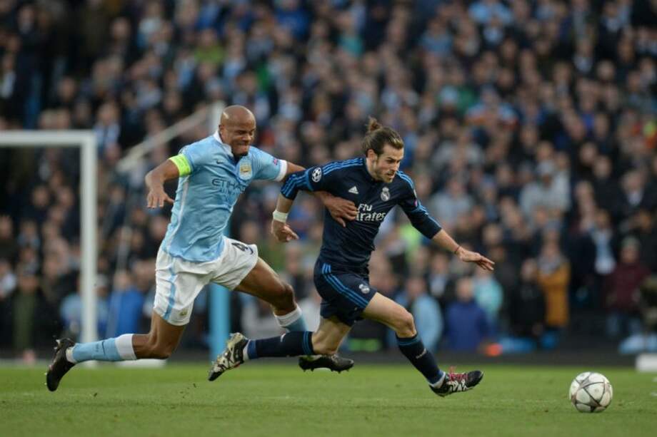 Gareth Bale (d) disputa un balón en el Ethiad Stadium. Foto: AFP
