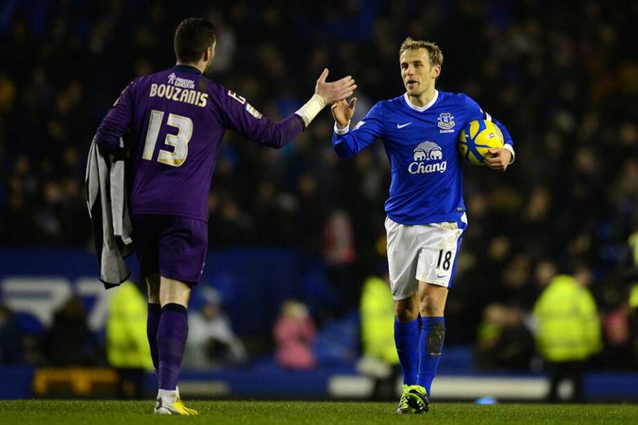 Phil Neville del Everton se saluda con Dean Bouzanis, arquero del Oldham. / AFP
