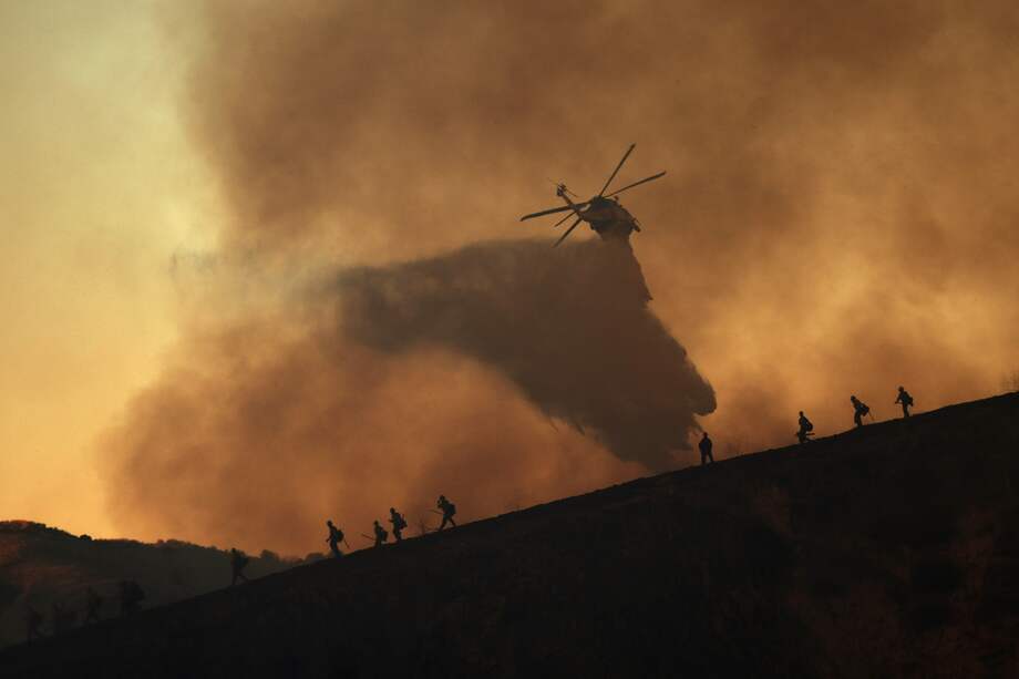Un helicóptero arroja agua al vecindario de Woodland Hills en Los Ángeles, California.