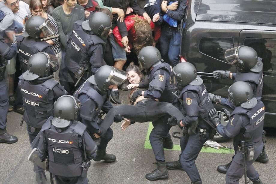 La policía española detiene a una joven enfrente de uno de los puestos de votación en Barcelona. / EFE