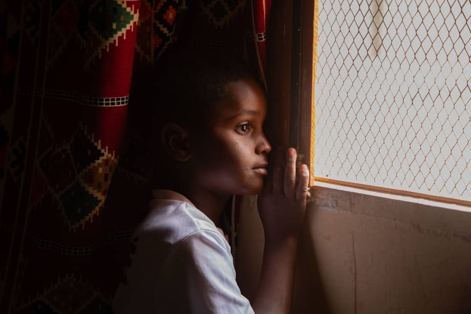 Ozman en una ventana de la casa familiar. Durante las horas más intensas del verano los saharauis permanecen dentro de sus casas. Entre las paredes de adobe y las telas que filtran la luz la vida se resguarda del calor. Campamentos de refugiados saharauis, Tinduf, Argelia.