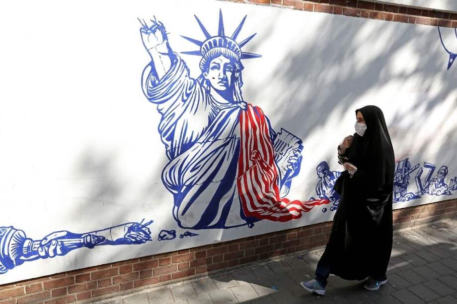 Una mujer pasa junto a un mural pintado en las paredes exteriores de la ex embajada de Estados Unidos en Teherán, capital de Irán.