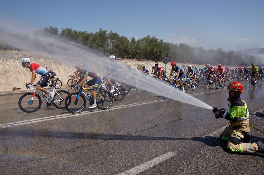 -FOTODELDÍA- CÓRDOBA, 23/08/2024.- Un bombero refresca al pelotón ciclista en la séptima etapa de la Vuelta a España, este viernes entre Archidona y Córdoba, de 180,5 kilómetros de recorrido. EFE/ Javier Lizón