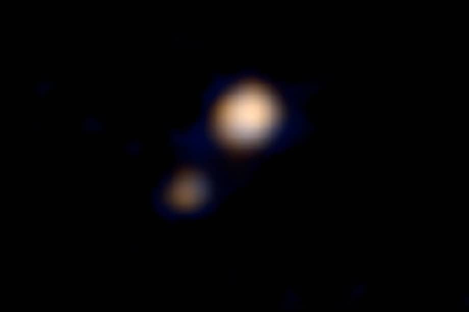La Agencia Espacial Estadounidense (NASA) publica el miércoles 15 de abril de 2015 la primera imagen en color de Plutón y su luna más grande, Caronte, obtenida por la sonda "New Horizons", que debería llegar al planeta enano el 14 de julio de este año. / AFP