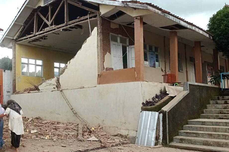 Una foto proporcionada por la Autoridad Nacional de Gestión de Desastres de Indonesia (BNPB) muestra a personas caminando cerca de un edificio derrumbado tras el terremoto de magnitud 5,6 en Cianjur, Indonesia, el 21 de noviembre de 2022.