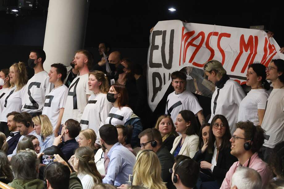 Activistas protestan con un cartel que dice "asesinato en masa de la UE" contra el paquete de migración y asilo durante una votación parlamentaria en una sesión plenaria del Parlamento Europeo en Bruselas, Bélgica, el 10 de abril de 2024.