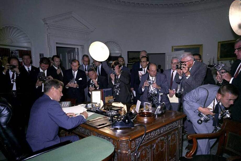 Foto de archivo fechada el 23 de octubre de 1962 que muestra al presidente estadounidense John F Kennedy (i) firmado el documento de intercepción de Armas a Cuba en el Despacho Oval, en la Casa Blanca, Washington, Estados Unidos.