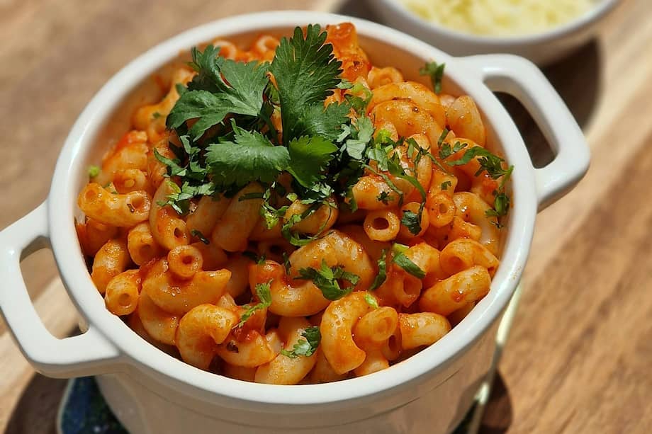 Espolvorea queso parmesano en estos macarrones cremosos con salsa de tomate para disfrutar.