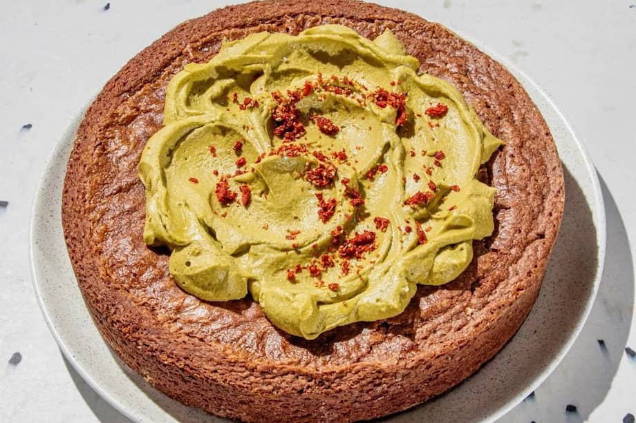 Torta de brownie melcochuda con ganache de chocolate blanco y pistacho con crocante de fresa deshidratada.