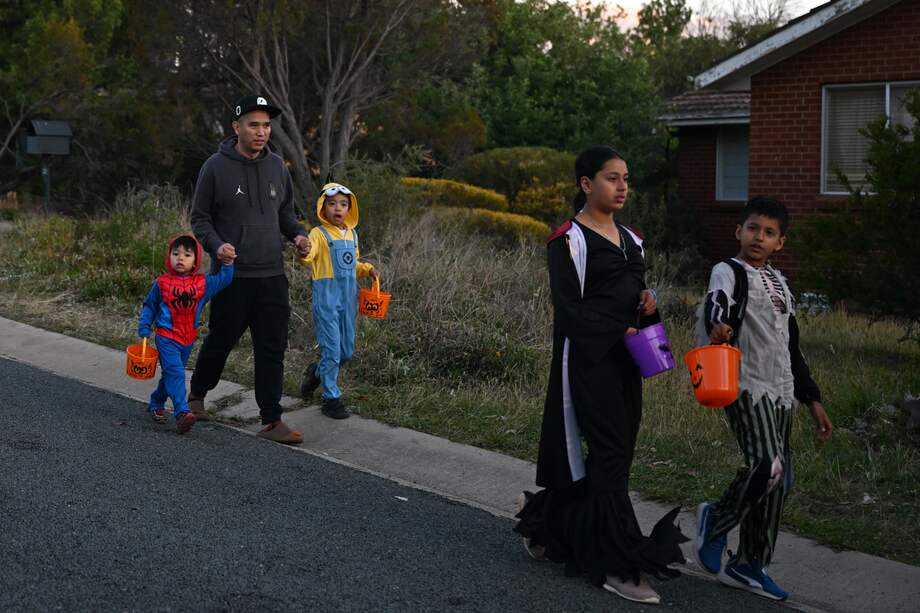 Foto de referencia de una familia saliendo a pedir dulces en Halloween con sus disfraces.