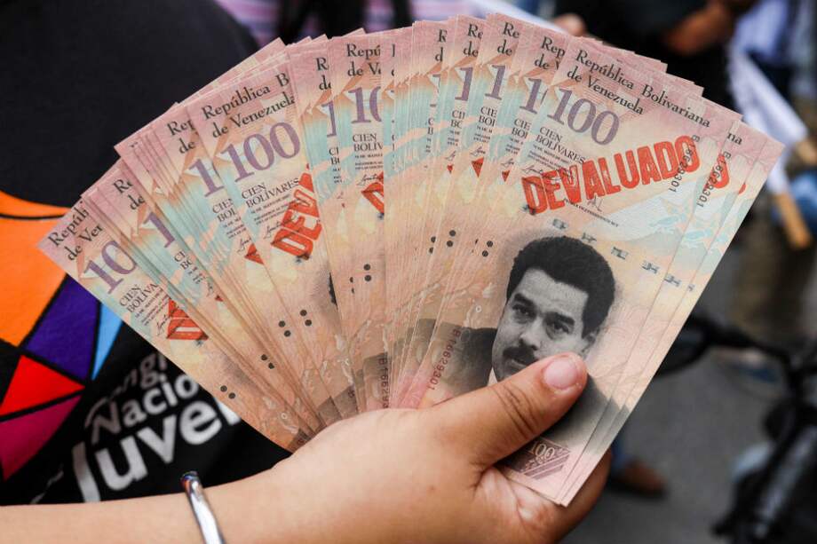 Una manifestante sostiene billetes con la cara del presidente Nicolás Maduro. / EFE