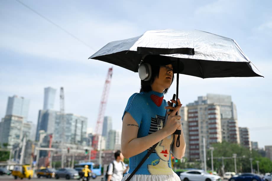 Una mujer camina por las calles de Pekín con una sombrilla en la mano, protegiéndose del sol.