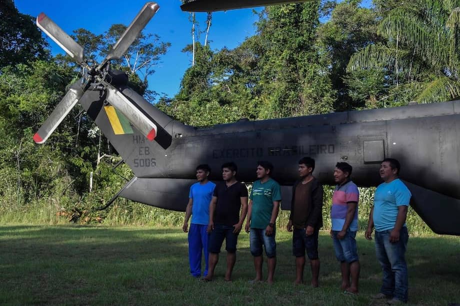 Indígenas Ye'kuana posan frente a un helicóptero en el 5 ° Pelotón de la Frontera Especial en Auari, estado de Roraima, Brasil, en medio de la nueva pandemia de coronavirus COVID-19. / AFP