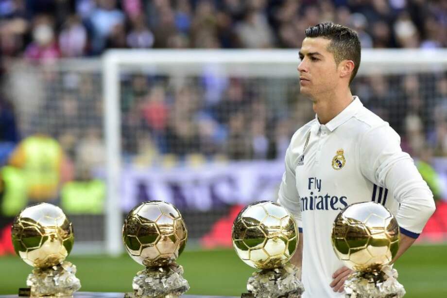 El portugués Cristiano Ronaldo posó este sábado en el estadio Santiago Bernabéu con los cuatro balones de oro que ha ganado. / AFP