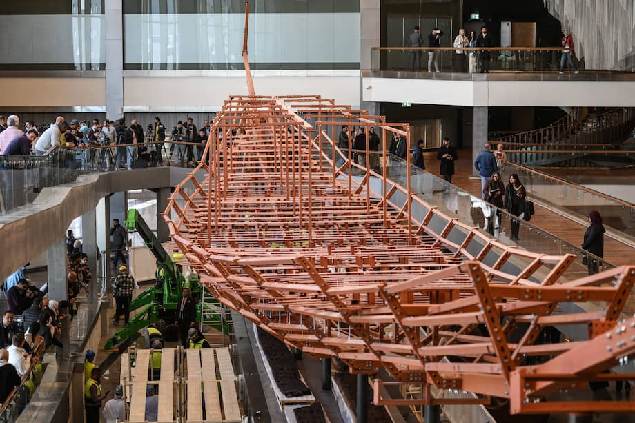 Los empleados del museo instalan tablones de madera antiguos del segundo barco del rey Keops sobre una estructura de metal en el Gran Museo Egipcio de Giza.