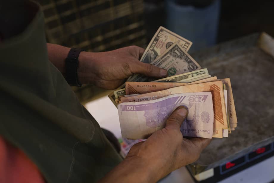 Un vendedor cuenta billetes de dólar y bolívar en un mercado de Caracas, Venezuela.