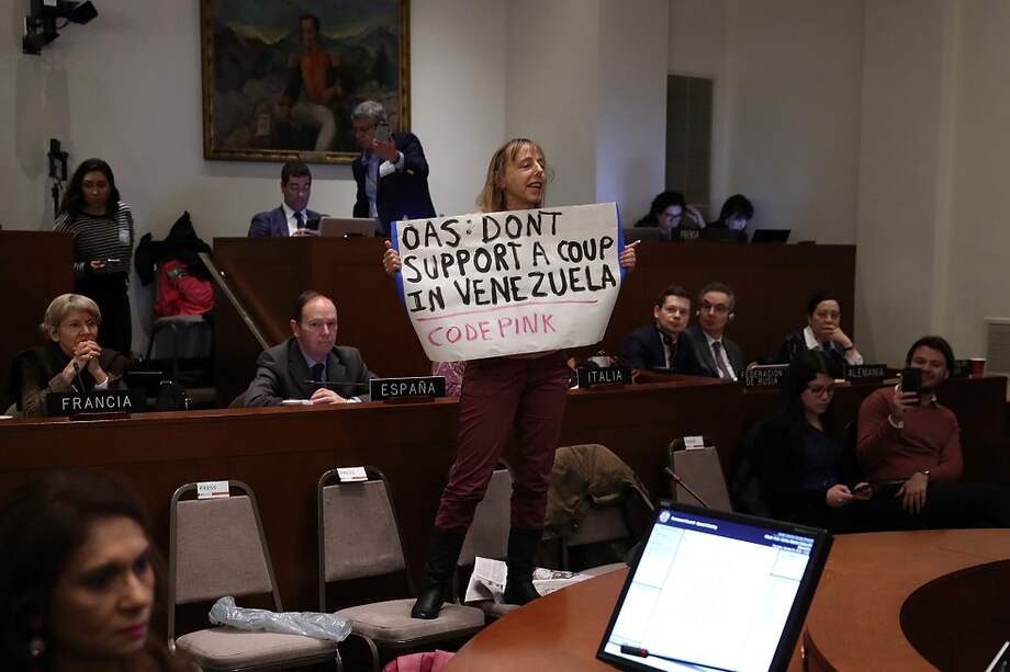 Una manifestante del colectivo Code Pink interrumpió la sesión extraordinaria en la OEA para expresar su apoyo al gobierno de Nicolás Maduro. / AFP