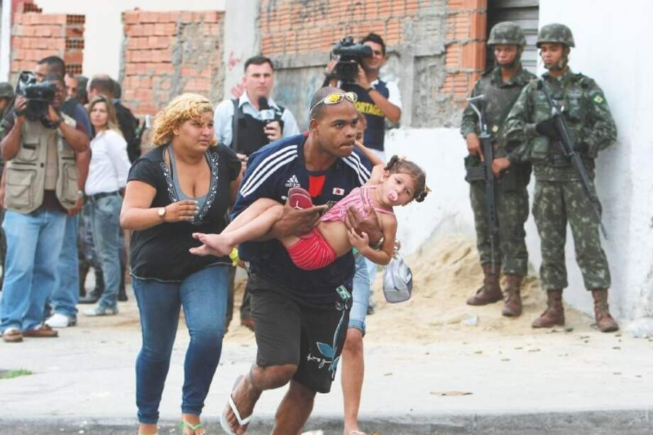 Civiles corren en medio de un enfrentamiento entre soldados brasileños y bandas narcotraficantes. / EFE