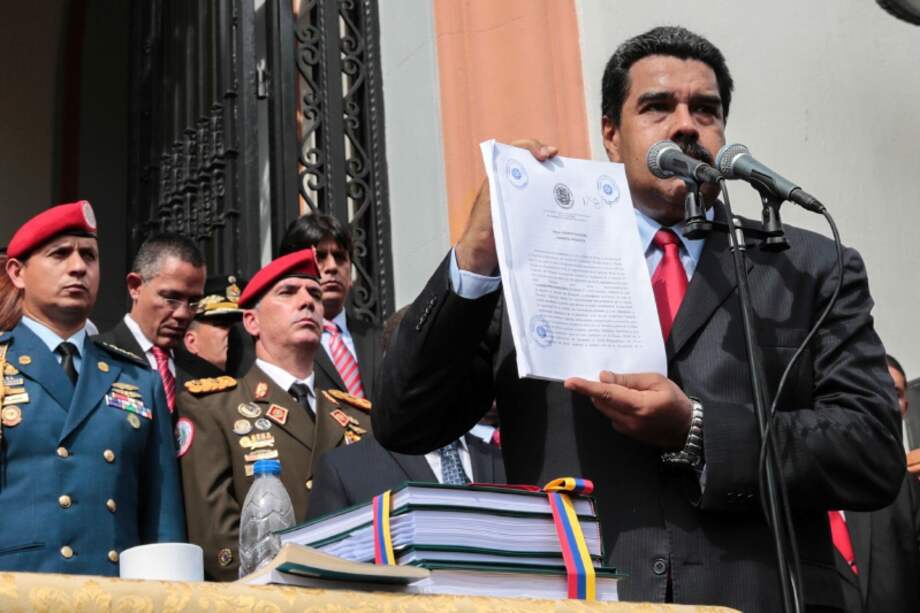 El presidente Nicolás Maduro muestra el decreto con el que aprobó el presupuesto 2017. / AFP