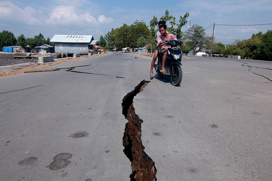 Un motociclista pasa cerca de una grieta en el suelo de Nagekeo que dejó el terremoto de 7,7 en Indonesia.