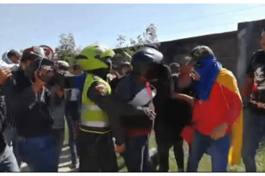 Momento en el que el uniformado aleja al agente de civil de los manifestantes y le quita el arma. / Captura de video.
