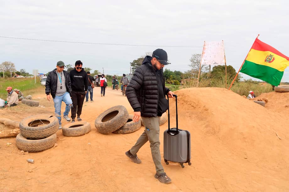 Personas cruzan por un bloqueo este martes, en una vía en San Julián (Bolivia).