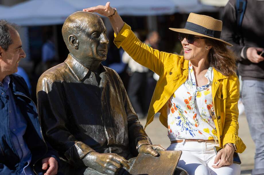 Unos turistas se sientan junto a la estatua de Pablo Ruiz Picasso de la Plaza de la Merced de Málaga en el día del 50 aniversario del fallecimiento del pintor malagueño, este sábado. EFE/ Álvaro Cabrera