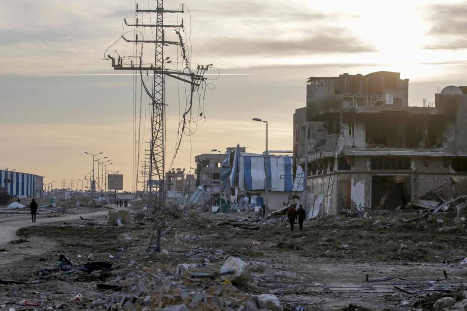Los palestinos caminan entre escombros, pasando por edificios destruidos a lo largo de la carretera Salah al-Din, en el sur de la Franja de Gaza.