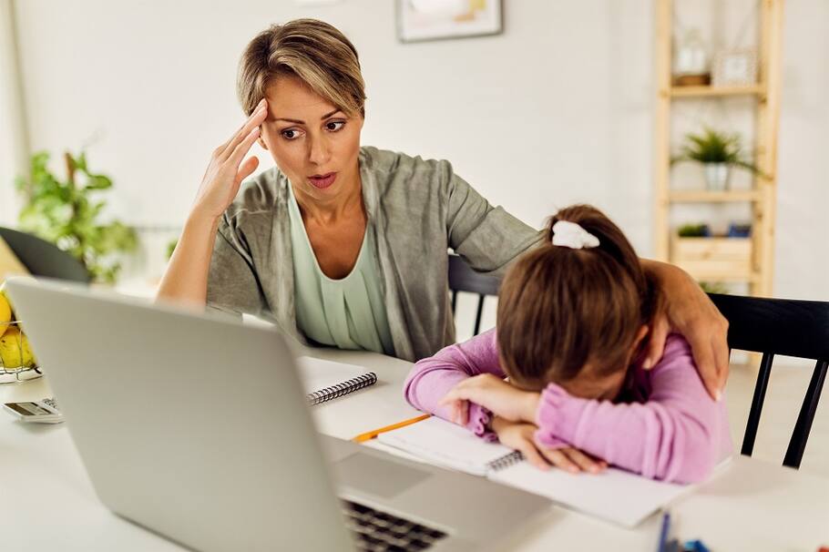 Little girl feeling sad while online learning and homeschooling with her mother. virtualidad padres en casa