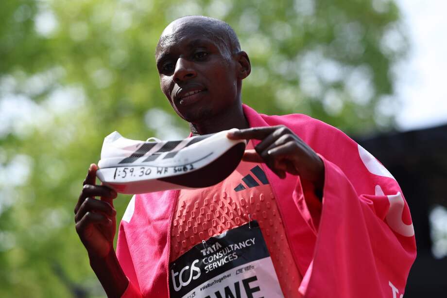 Sabastian Sawe sostiene las zapatillas que le dieron el récord de maratón.