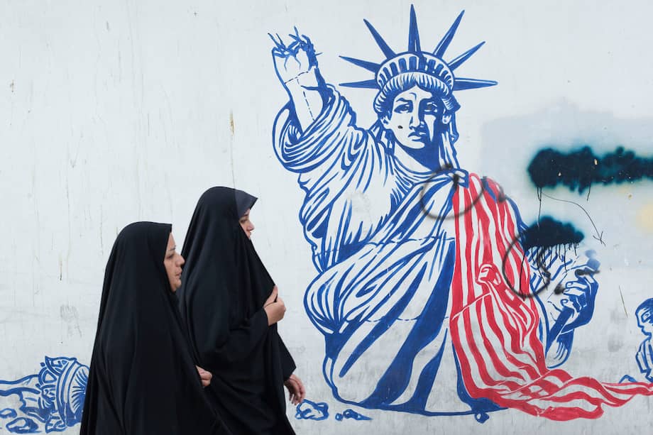 Dos mujeres pasan frente a un mural en Teherán con la Estatua de la Libertad en ruinas y mensajes de amenaza contra Israel.