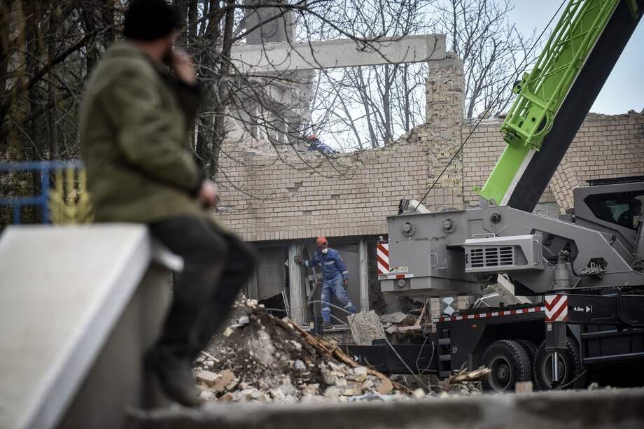 Un hombre observa el retiro de escombros en Rzhyshchiv, bajo asedio por los bombardeos rusos.