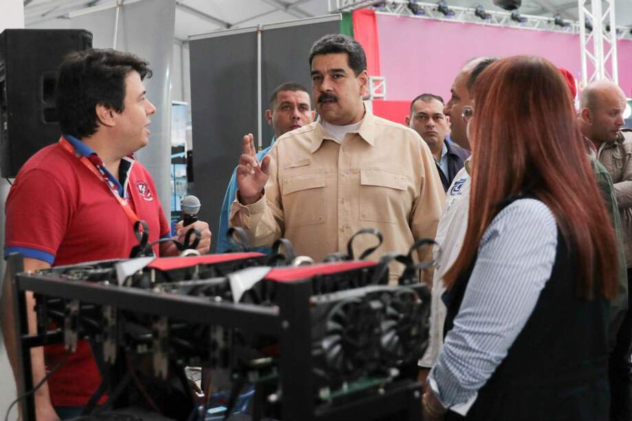 El presidente venezolano, Nicolás Maduro (C), habla frente a una computadora utilizada para extraer moneda cifrada. / AFP