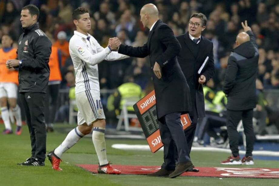 El colombiano James Rodríguez a su entrenador, el francés Zinedine Zidane, tras retirarse entre aplausos del campo del juego del Santiago Bernabéu, donde este miércoles fue protagonista. / EFE
