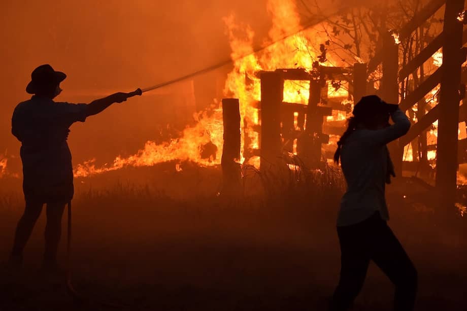 Residentes de la ciudad de Hillville, al norte de Sidney, intentan proteger su propiedad de los incendios. Se estima que en esta ciudad han arrasado una superficie del tamaño de unos 250.000 estadios de fútbol. / AFP
